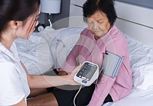 Female nurse checking blood pressure of a senior woman