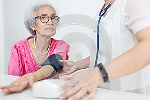 Female nurse checking blood pressure of a senior woman at home,Home carer checking patients blood pressure