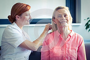 Female nurse combing hair of senior woman