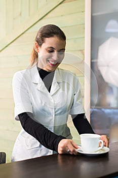 Female nurse at desk making coffee working in a modern office