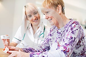 Female Nurse Discussing Medication With Senior Woman Patient