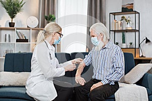 Female nurse or doctor gives a dose of insulin or vaccine to the senior man patient at the home visit. Vaccination at