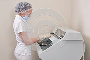 Female nurse doing sterilization of dental medical instruments in autoclave