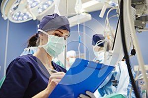 Female nurse examining all the parameters in operating room photo