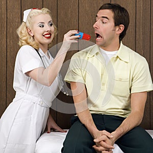 Female nurse giving man giant pill.