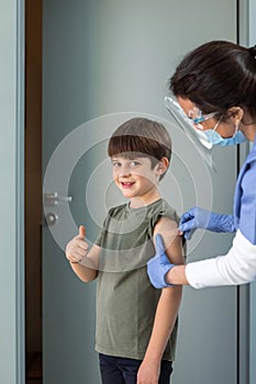 Female Nurse with gloves puts a band aid on a boy& x27;s arm after vaccination.