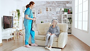 Female nurse helping senior woman getting dressed