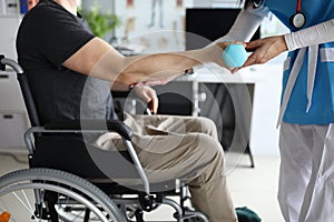 Female nurse helps lift dumbbell to disabled patient rehabilitation therapy