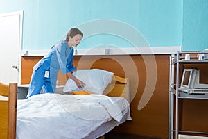 Female nurse holds a white pillow over the hospital bed in the h