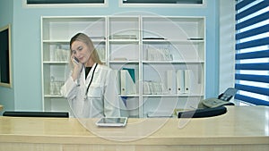 Female nurse at hospital reception answering phone calls and scheduling patient appointments