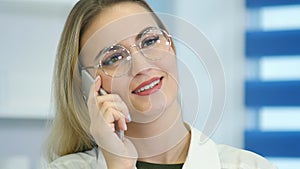 Female nurse at hospital reception talking on the phone