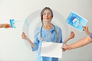 Female nurse with lot of work meditating on light background