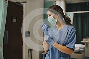 Female nurse with a mask putting on gloves