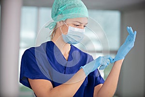female nurse with mask putting on gloves