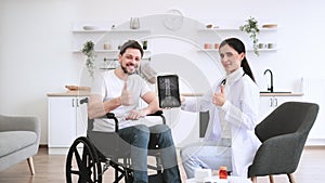Female nurse and mature man wheelchair user, showing x-ray scan of spine.