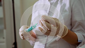 A female nurse prepares an injection syringe, fills a syringe from an ampoule with liquid, provides first aid. Woman`s