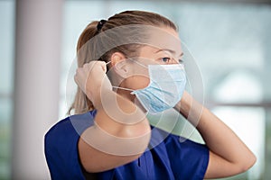 female nurse puts on protective face mask photo