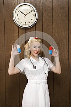 Female nurse in retro uniform holding giant pills.