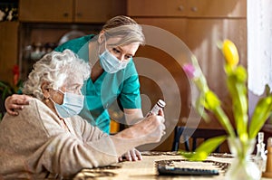 Female nurse reviewing prescription bottle with senior patient during home visit