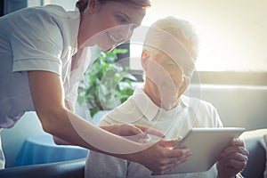 Female nurse showing medical report to senior man on digital tablet