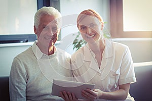 Female nurse showing medical report to senior man on digital tablet