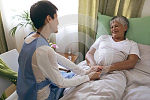 Female nurse taking care of senior female patient at retirement home