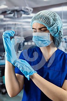 Female nurse wear red uniform putting on blue gloves