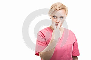 Female nurse wearing pink scrubs making look into my eyes