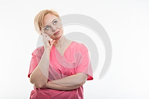 Female nurse wearing pink scrubs standing and thinking