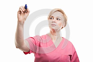 Female nurse wearing pink scrubs writing with blue marker