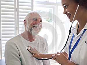Female Nurse Wearing Uniform Listening To Senior Male Patient\'s Chest In Private Hospital Room