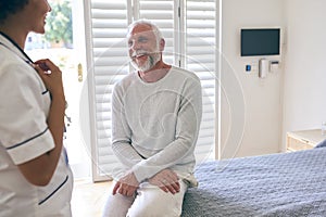 Female Nurse Wearing Uniform Meeting With Senior Male Patient's Chest In Private Hospital Room