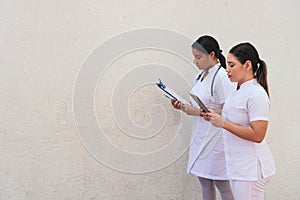Female nurses using digital tablet in hospital corridor