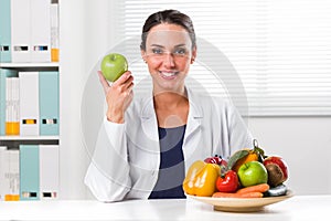 Female nutritionist holding a green apple photo