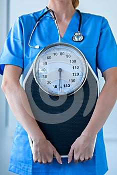 Female nutritionist holding weight scale in the consultation
