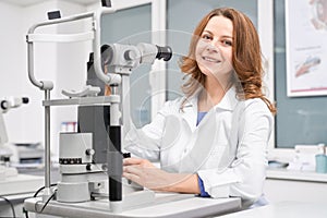 Female oculist checking eyesight with slit lamp in clinic