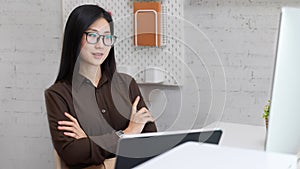 Female office worker arms crossed and looking on computer screen in office room