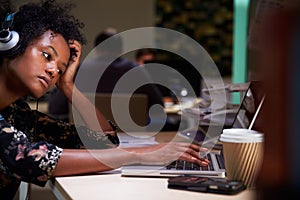 Female Office Worker With Coffee At Desk Working Late