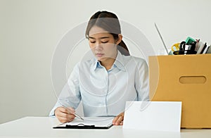 A female office worker, dissatisfied with the termination, packs her belongings in a cardboard box and sits down desperately