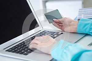 Female office worker hands holding credit card, typing on the keyboard of laptop, online shopping detail close up.