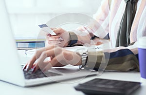 Female office worker hands holding credit card, typing on the keyboard of laptop, online shopping detail close up.