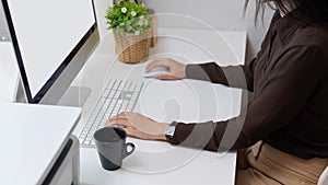 Female office worker hands using computer device on white desk in office room