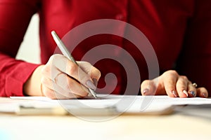 Female office worker holding silver pen filling out some application form