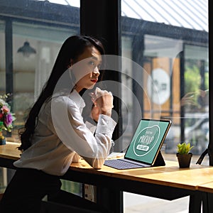 Female office worker sitting with mock up digital tablet in cafe