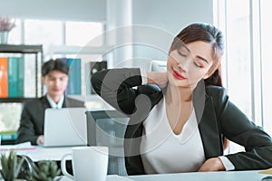 Female office worker suffering from office syndrome, using her hand to rub on her neck pain