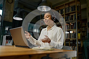 Female office worker wearing headphones working on laptop computer