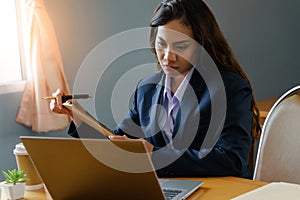 Female office worker wears dark blue business suit working with document file and pile of work paper in serious emotional face in