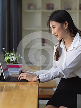 Female office worker working with digital abet on wooden bar in cafe