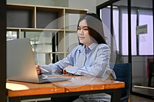 Female office worker working on her business assignment project, using laptop