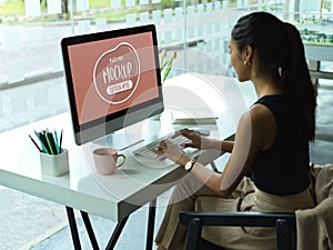 Female office worker working on mock up computer on desk